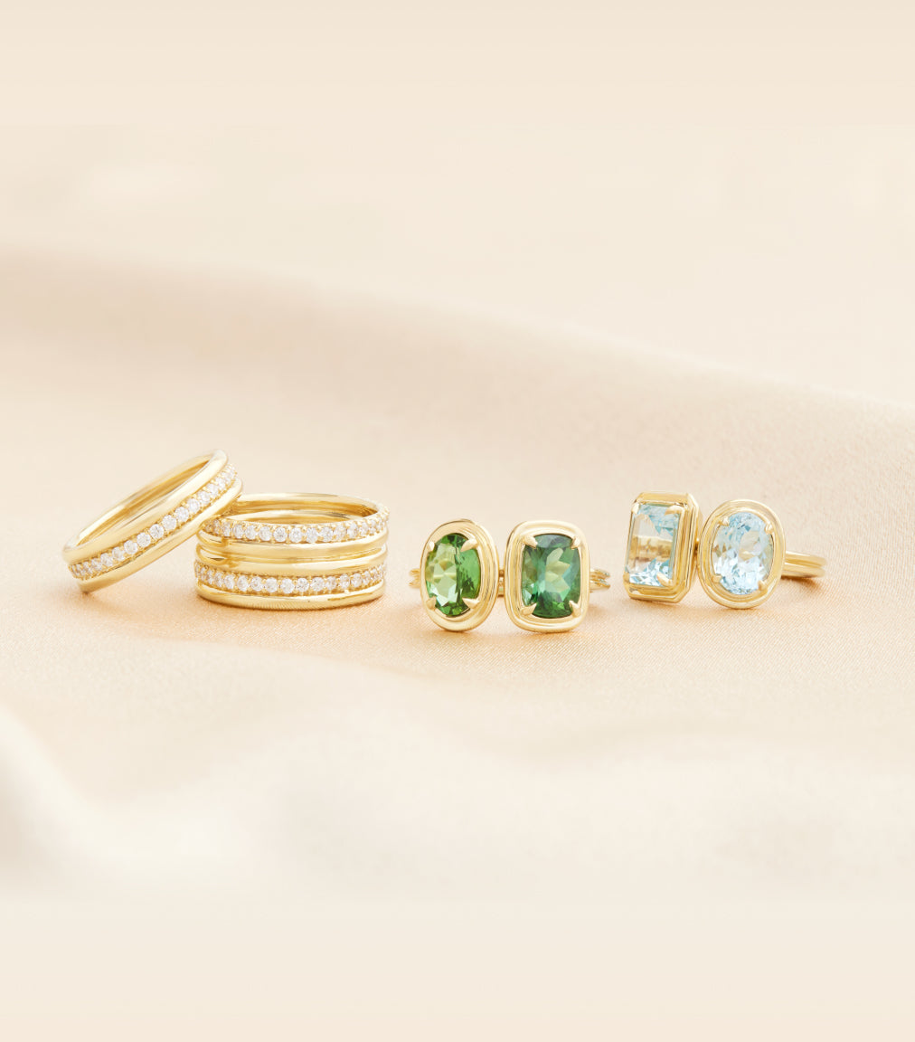 Gold jewelry set with green gemstones on a beige background