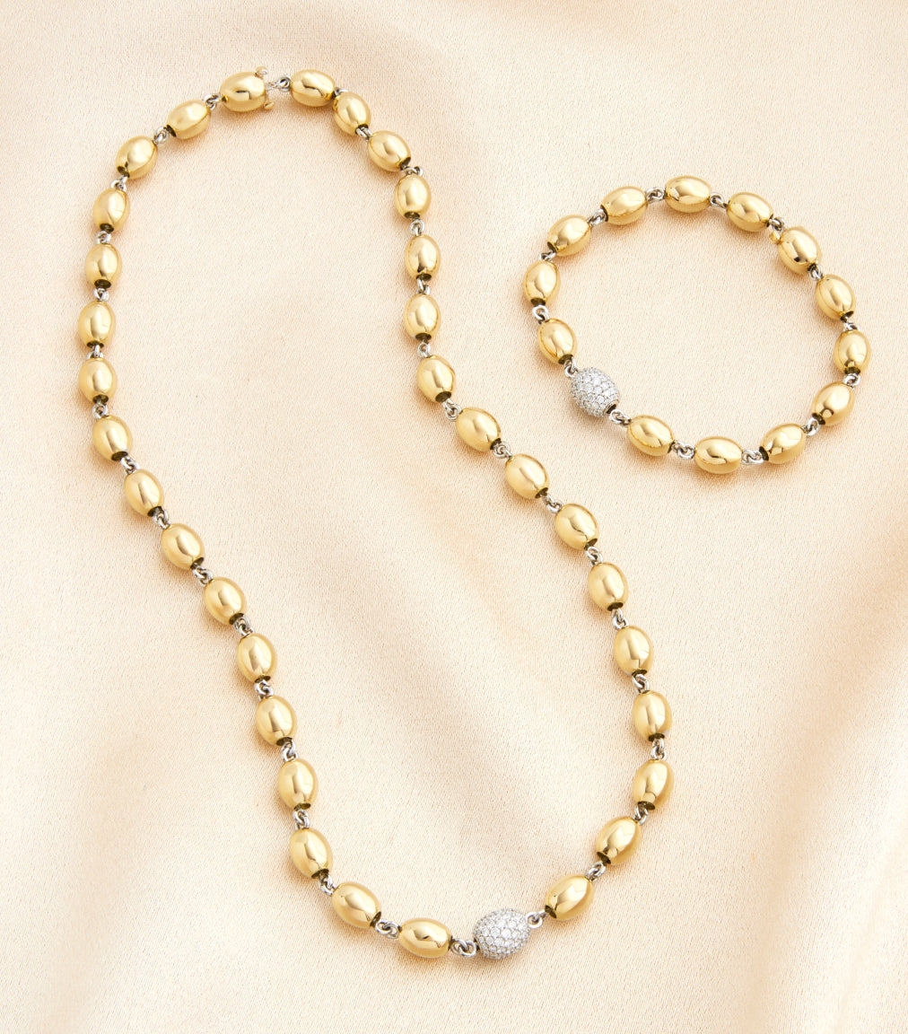 Gold necklace and bracelet set on a beige background